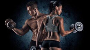 a fit man and woman in gym wear standing with their backs to each other lifting weights